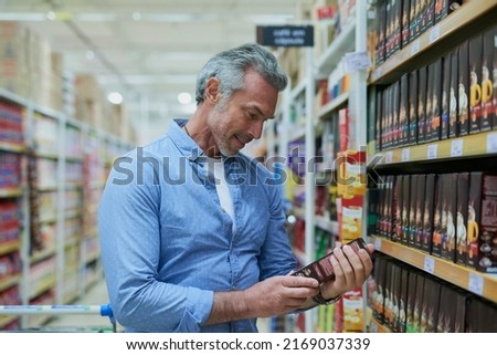 Looks good, Ill buy it. Shot of a handsome mature man reading the label on a box while shopping in a grocery store. Royalty-Free Stock Photo #2169037339