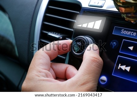 Driver hand adjust volume control on the car radio dashboard Royalty-Free Stock Photo #2169043417