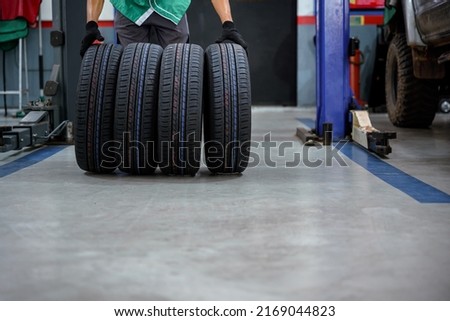 male tire changer In the process of bringing 4 new tires that are in stock in order to change the wheels of the car at a service center or an auto repair shop for the automobile industry