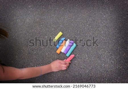 girl draws a rainbow, sun, car with chalk on the asphalt. Selective focus