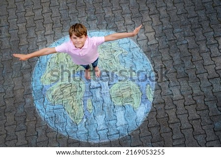 Little school boy with earth globe painting with colorful chalks on ground. Positive kid child. Happy earth day concept. Creation of children for saving world, environment and ecology. Royalty-Free Stock Photo #2169053255