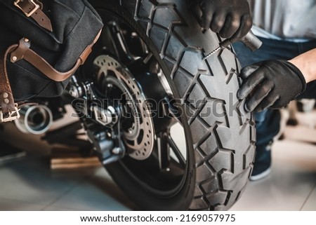 Rider use a tire plug kit and trying to fix a hole in tire's sidewall ,Repair a motorcycle flat tire in the garage. motorcycle maintenance and repair concept Royalty-Free Stock Photo #2169057975