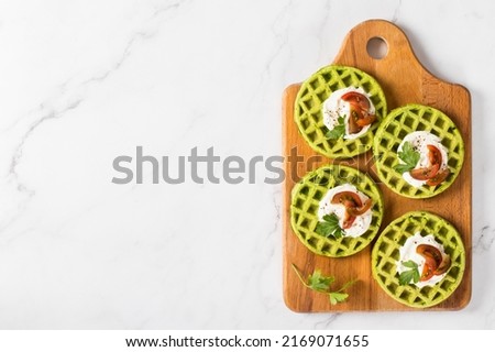 Spinach waffles with cottage cheese, cherry tomatoes and parsley, on a wooden board. Light gray background. Top view. Copy space