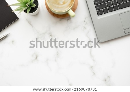 White marble office desk table with laptop computer, cup of latte coffee and office supplies. Top view with copy space, flat lay.