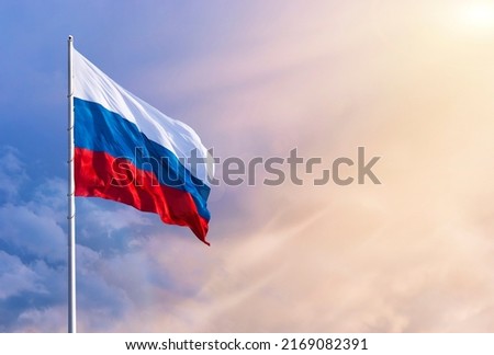 Waving Russian flag against a blue sky with clouds and empty space for text. Room for text. National flag of the Russian Federation. Bright sunlight. Royalty-Free Stock Photo #2169082391