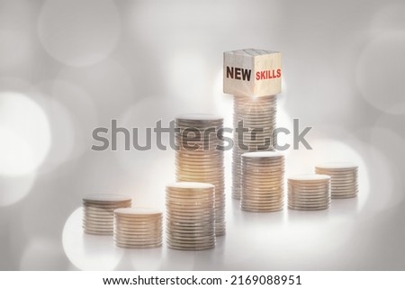 New skills on cube on stack of coins on abstract background. Return on investment with education concept and reskilling and up skilling idea