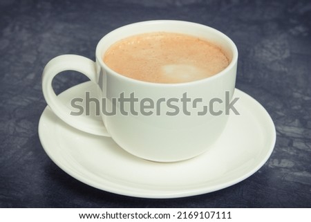 Cup of fresh prepared coffee with milk on dark background