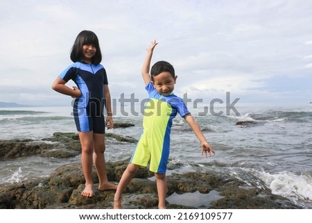a teenage girl with a boy taking a photo on a rock on the beach, Pelabuhan Ratu, May 1, 2012