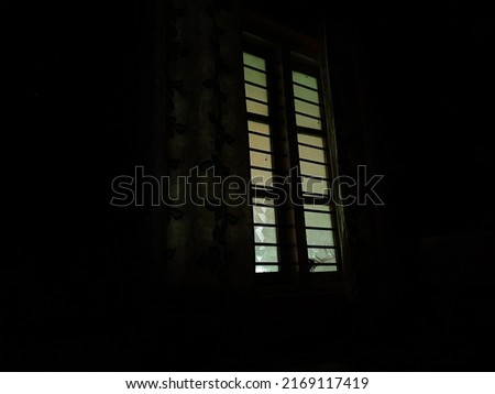 Stock photo of rectangle shape window with grill in living room with floral curtains. Picture captured under darkness at Bangalore,Karnataka,India. selective focus.