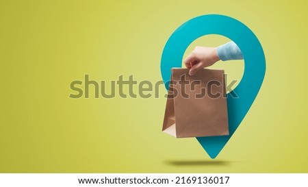 Hand holding a food delivery bag and location pin, fast food delivery concept Royalty-Free Stock Photo #2169136017