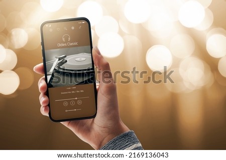 Woman holding a smartphone and listening to music online, she is playing old songs, blank copy space Royalty-Free Stock Photo #2169136043