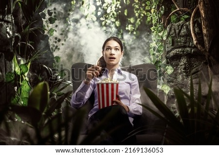 Young woman having an immersive cinema experience, she is surrounded by a wild jungle Royalty-Free Stock Photo #2169136053