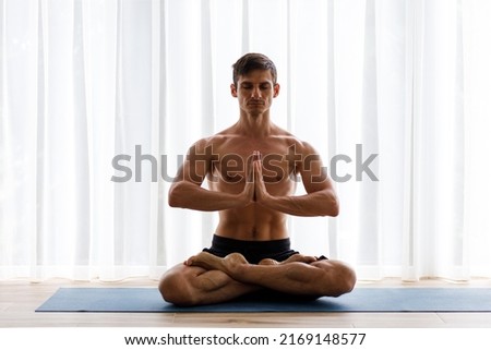 Young strong man doing yoga meditation breathing routine in the morning. Full lotus pose image