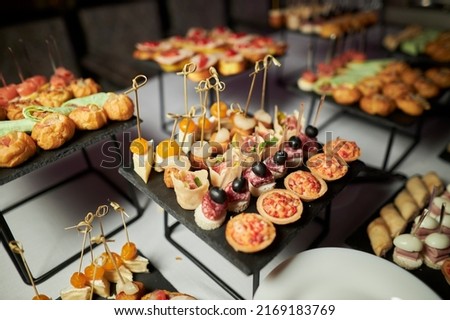 light snacks for the holiday, catering. Various light snacks. Catering plate. Assortment of sandwiches on the buffet table. meat, fish, vegetable canapes. Royalty-Free Stock Photo #2169183769