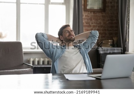 Satisfied by work done employee put hands behind head breath fresh-conditioned air looks carefree sit at workplace desk with laptop enjoy comfort break, relax alone in modern office. No stress concept Royalty-Free Stock Photo #2169189941