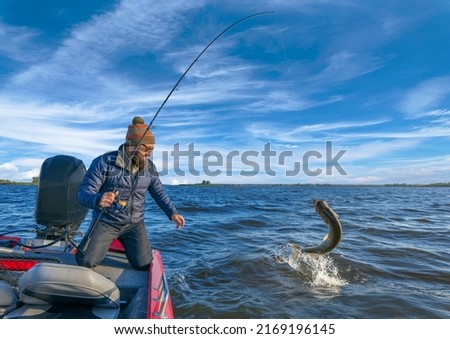Pike fishing. Fisherman catch big muskie fish with splash in water Royalty-Free Stock Photo #2169196145
