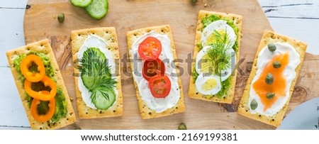 Top down view of everything crackers with various toppings on a wooden board. Royalty-Free Stock Photo #2169199381