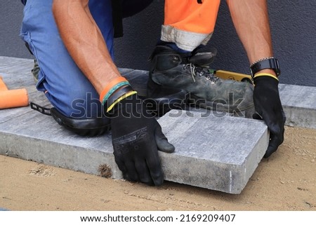 The foreman places the paving stones.