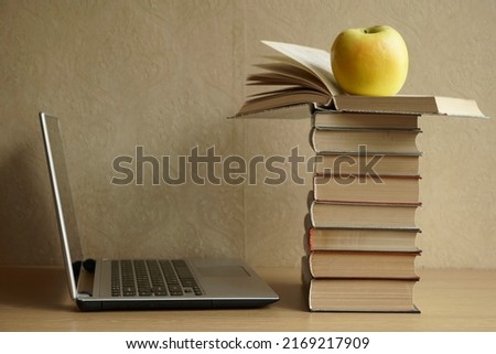 Stack of  books with green apple. Silver laptop - side view. Back to school idea. 