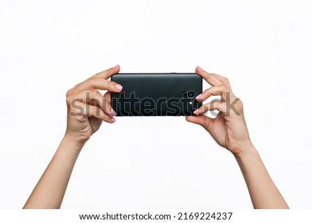 Mobile phone with photo camera in female hands isolated on a white background. Blank with an empty copy space for the design. Mockup of a smartphone. A young woman takes picture 