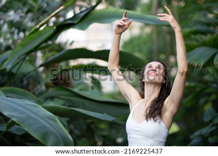 Female meditating and practicing yoga in tropical rainforest. Beautiful young woman practicing yoga outdoor with tropical forest in background.