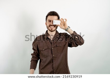 Happy casual man wearing casual clothes posing isolated over white background showing plastic credit card near face. Shopping and finance concept.