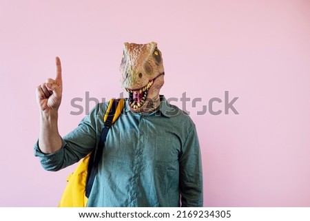 Man in lizard mask on pink background showing one fingers.