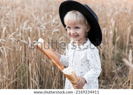 Beautiful portrait of a young child in a field. Children with bread. Little girl in cereal field. Happy baby girl on field of wheat with bread. 