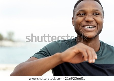 Portrait view of the african american man laughing out loud while standing at the seashore and preparing to the jogging. Stock photo