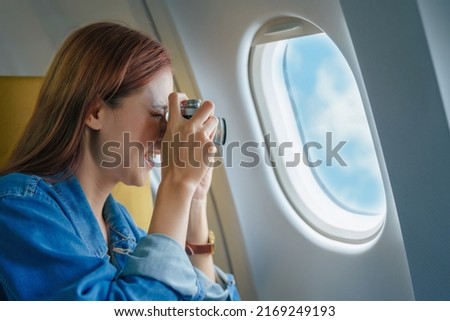 Travel, Portrait of a smiling Asian female tourist with a camera taking pictures of the sky during her flight