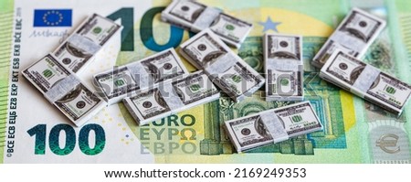 bundles of miniature 100 dollar banknotes on 100 euro banknote background for design purpose