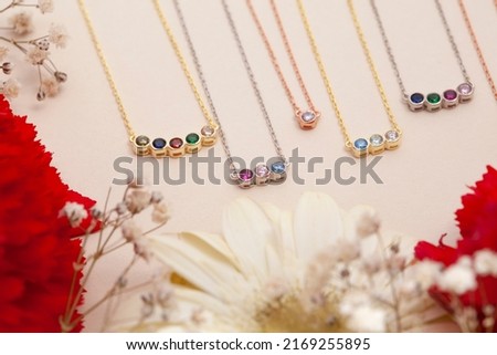 necklaces on a cream background with colorful flowers. Image for e-commerce, online sale, jewelry sale. Royalty-Free Stock Photo #2169255895