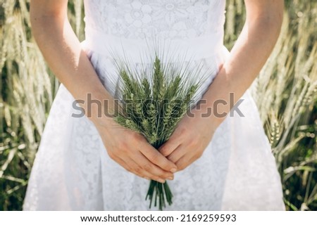 Carefree woman enjoys nature in a wheat field and touches ears of ripe yellow wheat with her hand. The girl travels. A woman farmer in the field checks the ripening crop