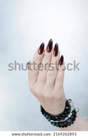 Female hands with long nails and black and red nail polish