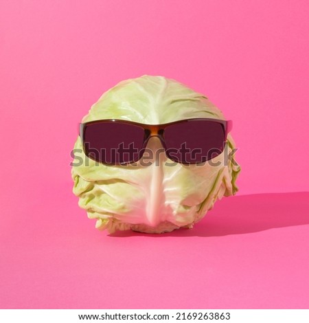 Cabbage head with sunglasses on pink background. Funny food concept. Human head representation concept.