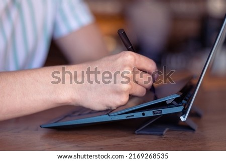 Digital artist make drawing on laptop. Close up look of graphic designer drawing with pencil on graphic drawing board with hand. Freelancer creating new creative digital content on his notebook. 