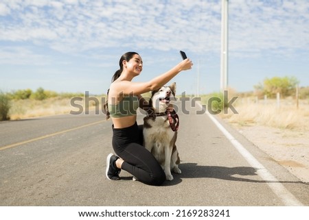 Gorgeous latin woman smiling while taking a selfie with his husky dog while exercising outdoors Royalty-Free Stock Photo #2169283241