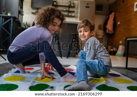 Brother and sister siblings small caucasian boy and girl child play twister game on the floor at home alone real people family growing up leisure concept copy space Royalty-Free Stock Photo #2169306299