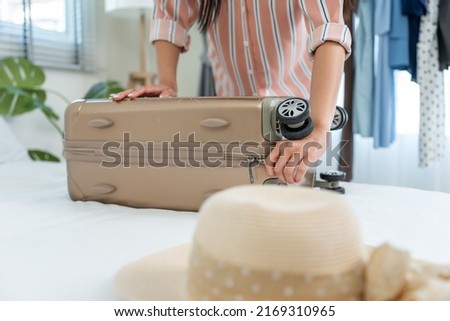 Close up hands of young woman preparing clothes and packing a suitcase. Attractive female tourist traveler feel happy and relax while preparing luggage on bed, ready to travel on holiday vacation trip Royalty-Free Stock Photo #2169310965
