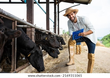 Portrait of Caucasian dairy farmer male working alone outdoor in cow farm. Young attractive man agricultural farmer check and examining cows animal in cowshed with happiness at livestock farm industry Royalty-Free Stock Photo #2169311065