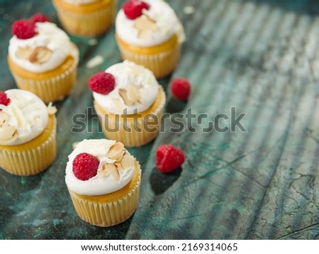 Light fresh muffins with cream, decorated with raspberries and almonds on a green napkin. Food background. Food design, sweet food, holiday, birthday, restaurant, hotel, patisserie.