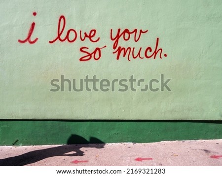 Street art mural in red cursive writing on green background with a dark green line at the bottom "I love you so much" taken in Austin Texas Royalty-Free Stock Photo #2169321283