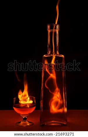 Bottle and glass in flame isolated on black background