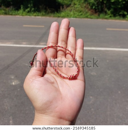A red rope rests on his hand with a road in the background