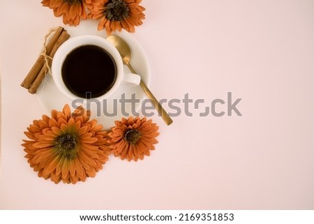 White cup of coffee with cinnamon and orange flowers on a white background. Beautiful and elegant invitation card with copy space to the right of the image.