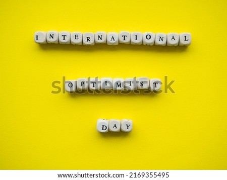 international optimist day. Yellow background with text International Optimist Day on wooden cubes and with place for your text. Copy space.