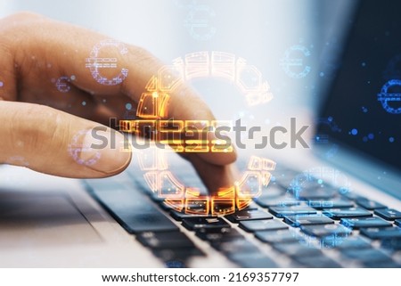 Close up of hands using laptop computer keyboard with abstract glowing euro sign hologram on blurry background. Online banking, technology, data and finance concept. Double exposure