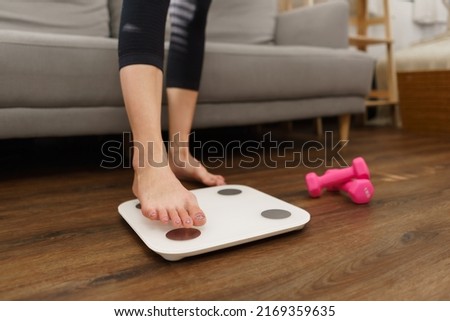 Healthy and weight loss concept, Young Asian woman stepping on weighing scales after weight control.