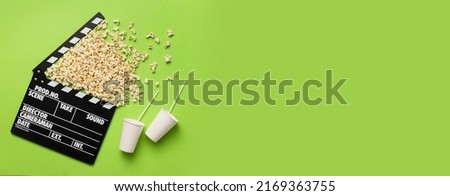Tasty popcorn with cups of cola drink and movie clapper on green background with space for text