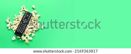 Modern TV remote control with popcorn on green background with space for text